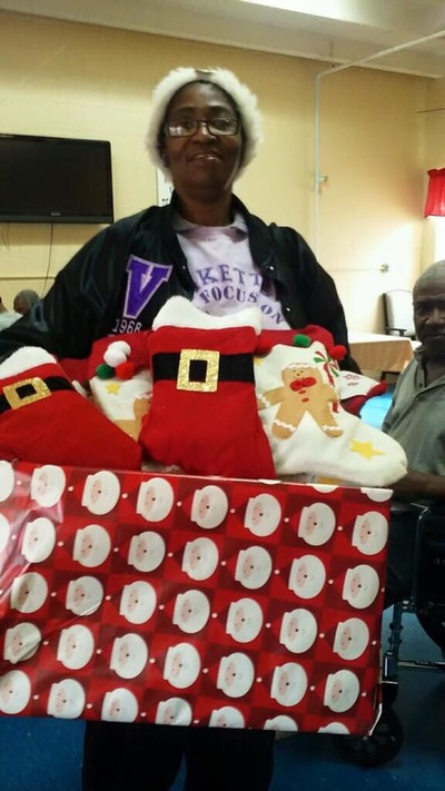 A member holding a box filled with Christmas stockings for nursing home residents