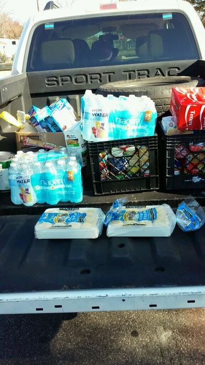 A truck bed loaded with water, food, and holiday donations ready for delivery