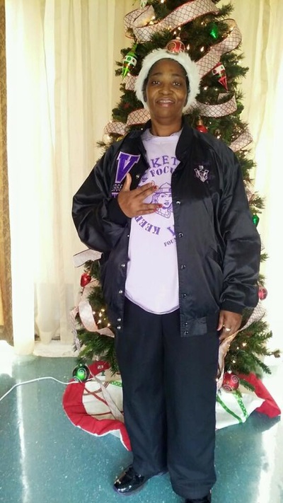A member in a Santa hat beside the Christmas tree during holiday outreach